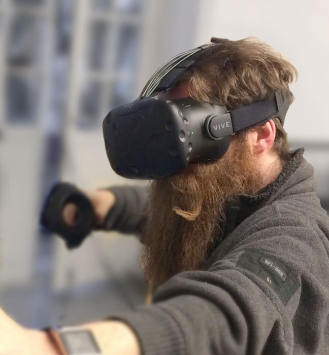 Foto: junger Mann mit langem Vollbart und VR-Headset
